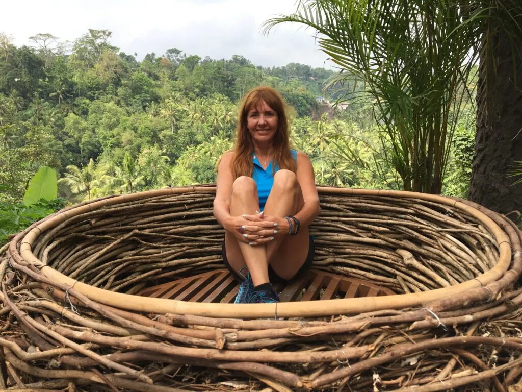 The Best Time to Visit Bali (and Why) Smiling person in large wooden nest, jungle background.