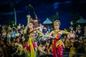 Two women perform traditional Balinese dance in colorful costumes during a festival.
