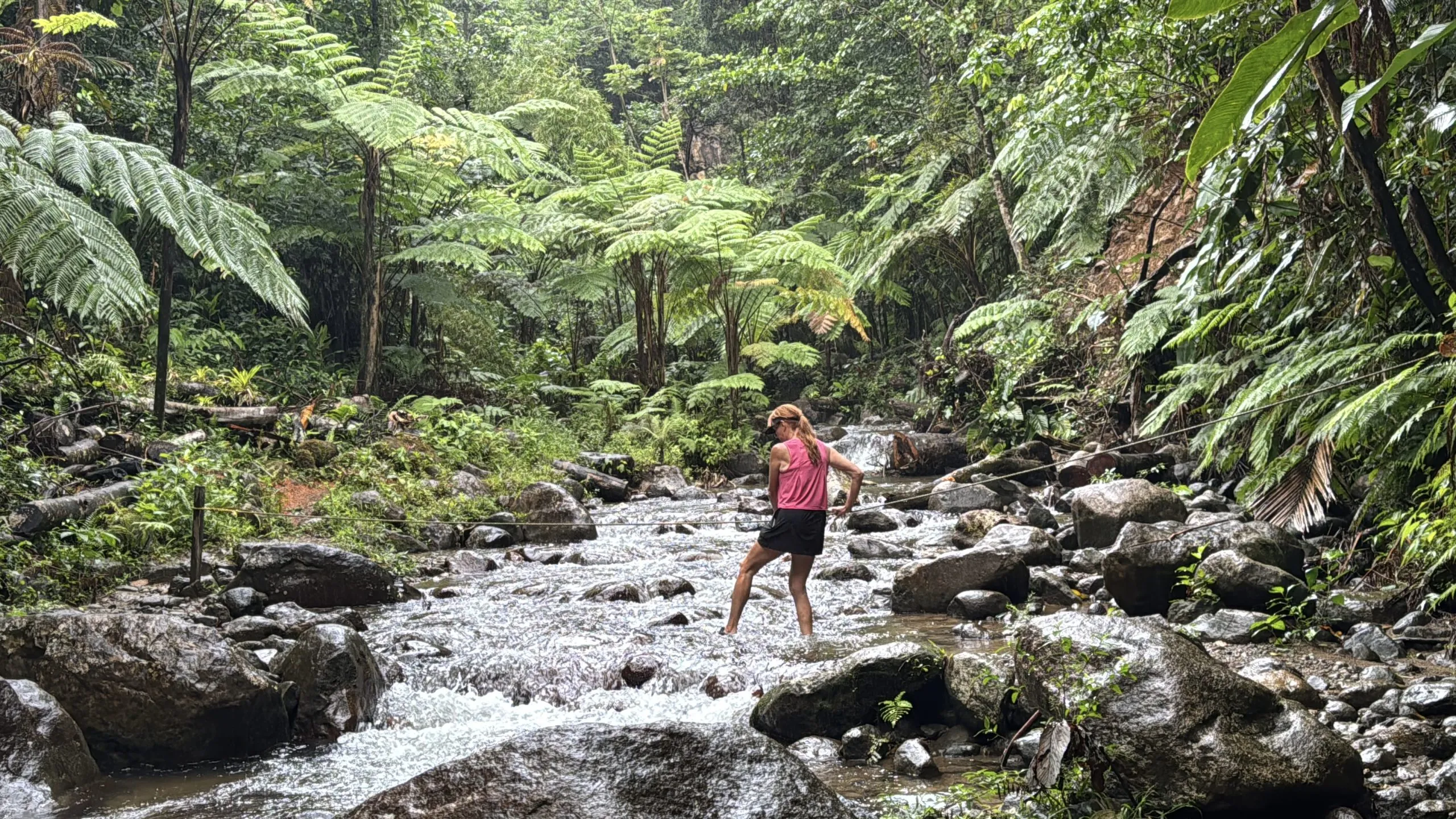 Woman crossing rocky forest stream