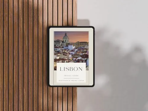 Tablet displaying Lisbon travel guide on wooden table.